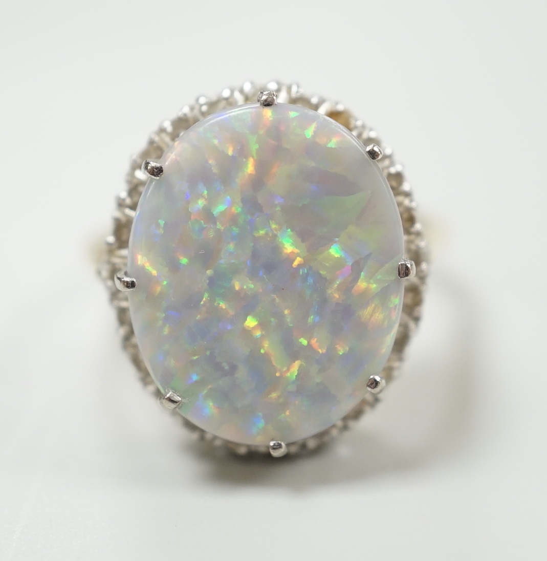 An 18ct, white opal and diamond chip set oval cluster ring, size L, gross weight 8.1 grams.
